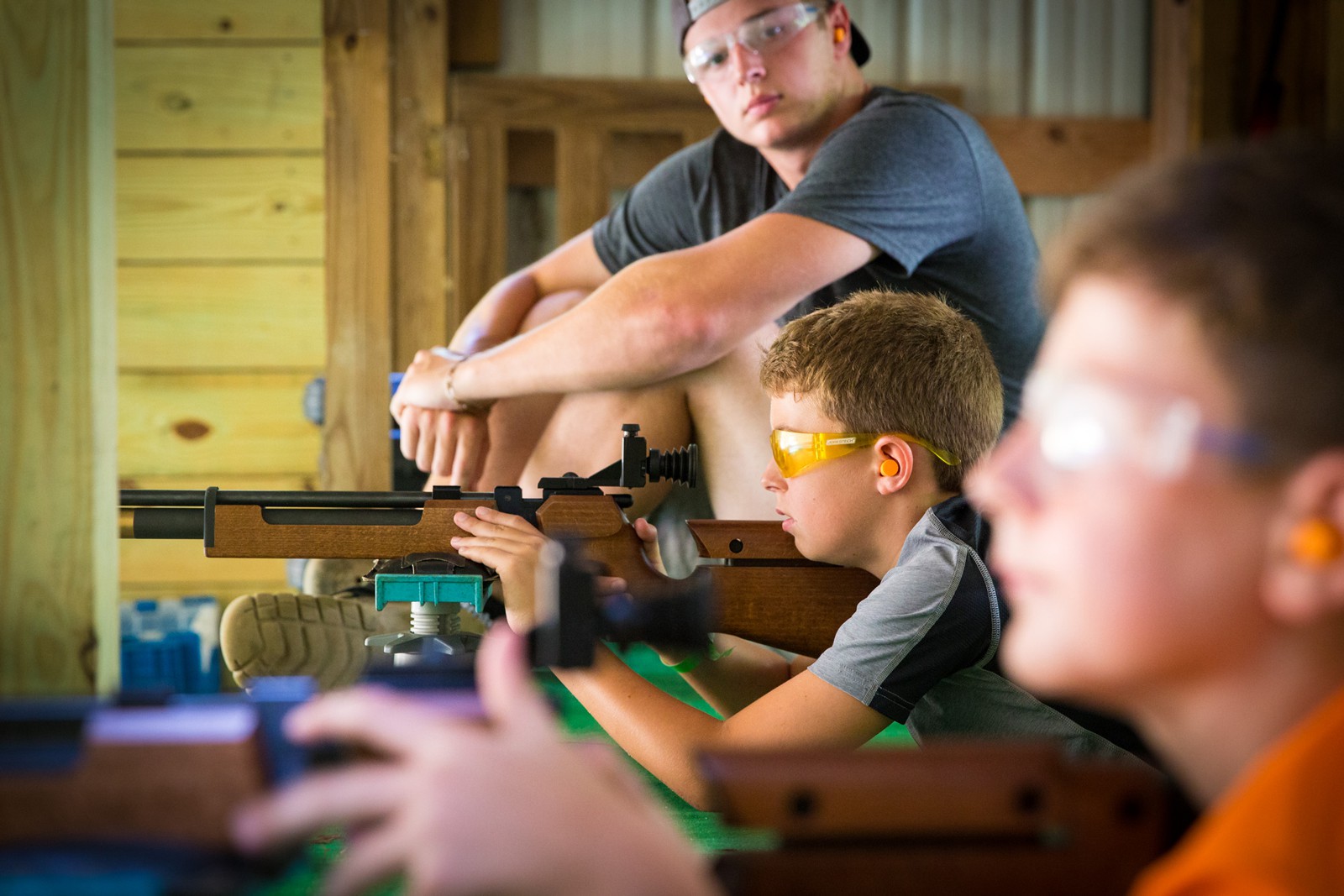 Boy with safety glasses shooting a rifle at a range