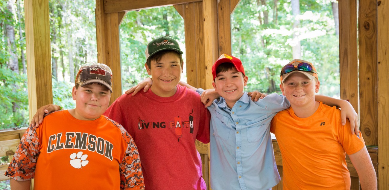 four summer camp boys hugging