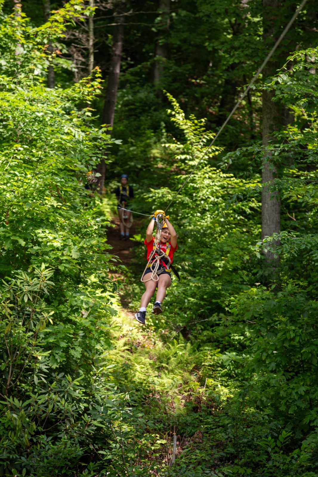 Camper riding a zipline through the forest