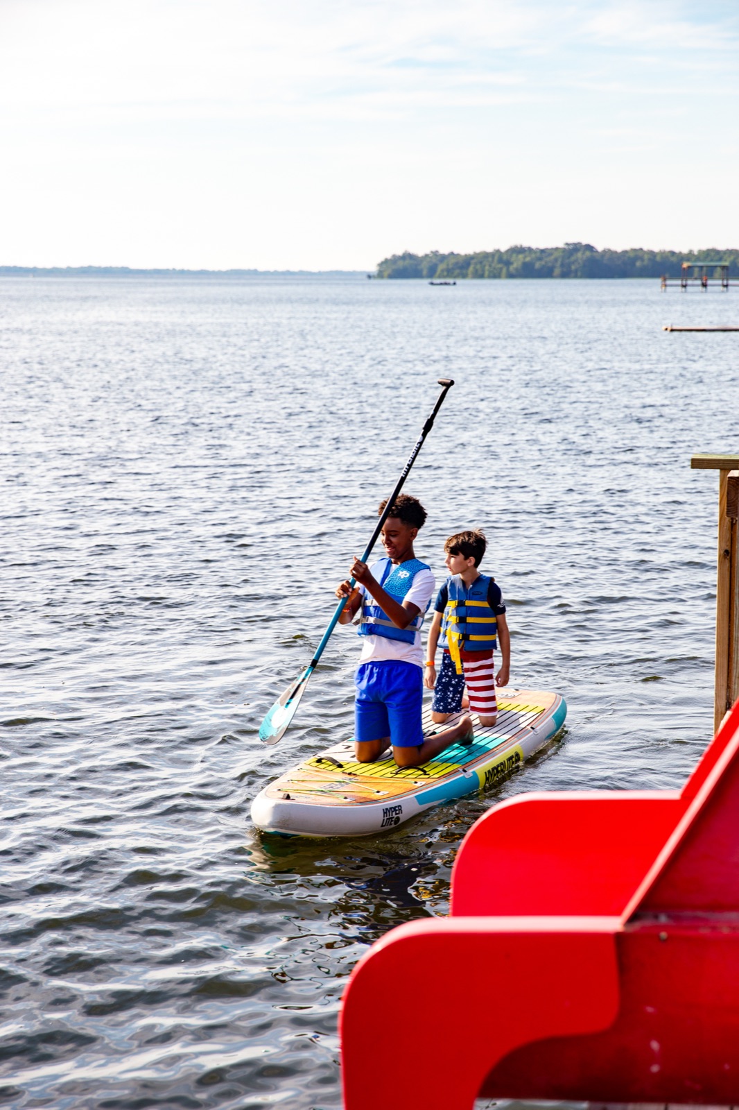 Two campers in life jackets on a paddleboard on the lake
