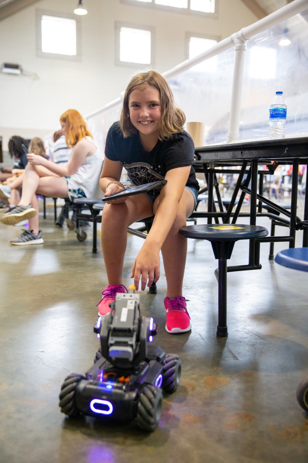 Smiling camper driving a robot rover with a tablet