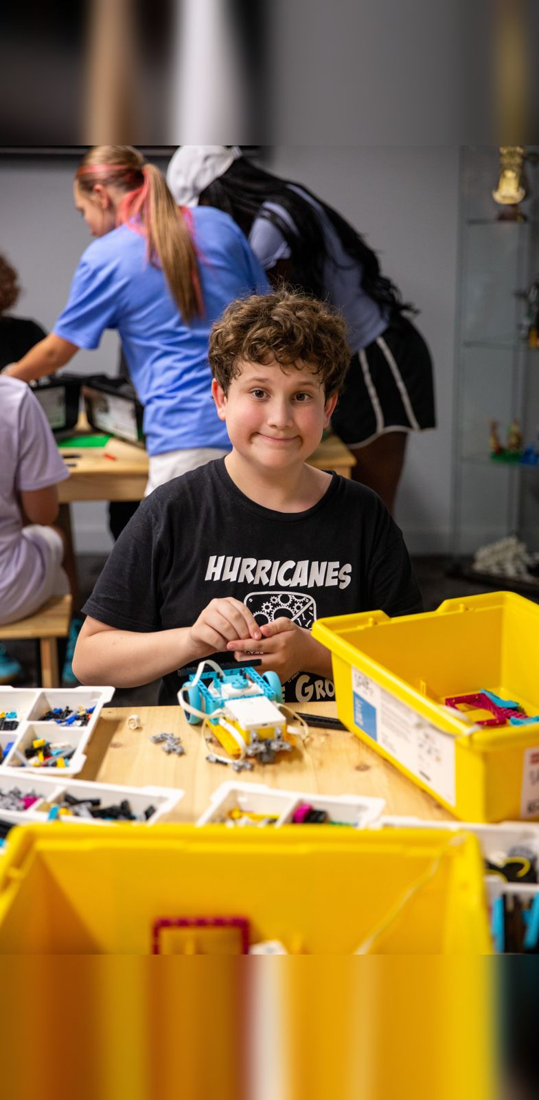 Camper building a LEGO robotics project at a worktable