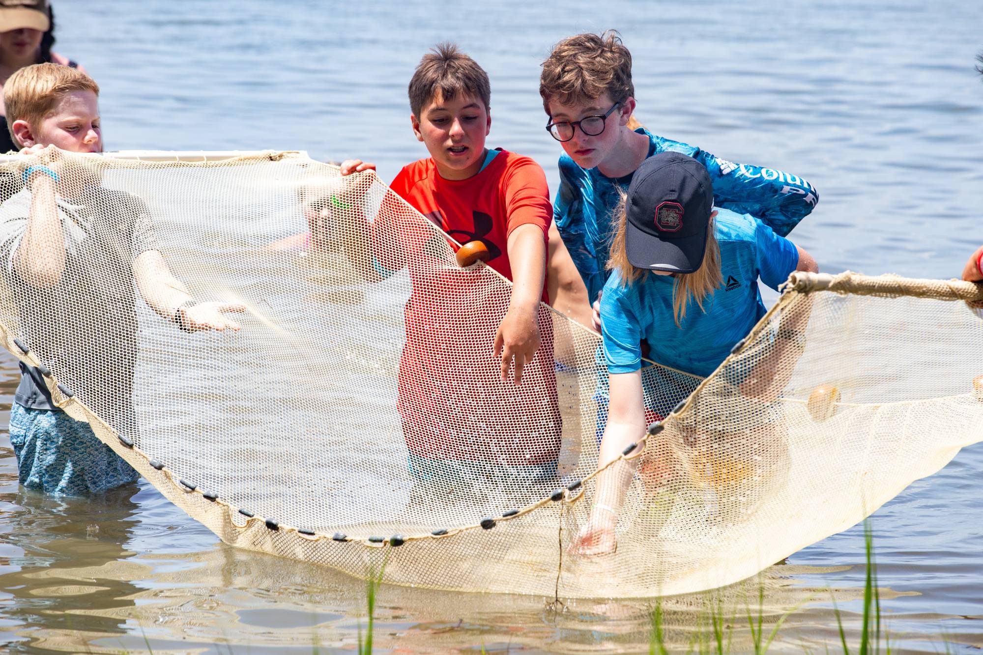 Campers wading in the lake and pulling a seine net to see what they caught